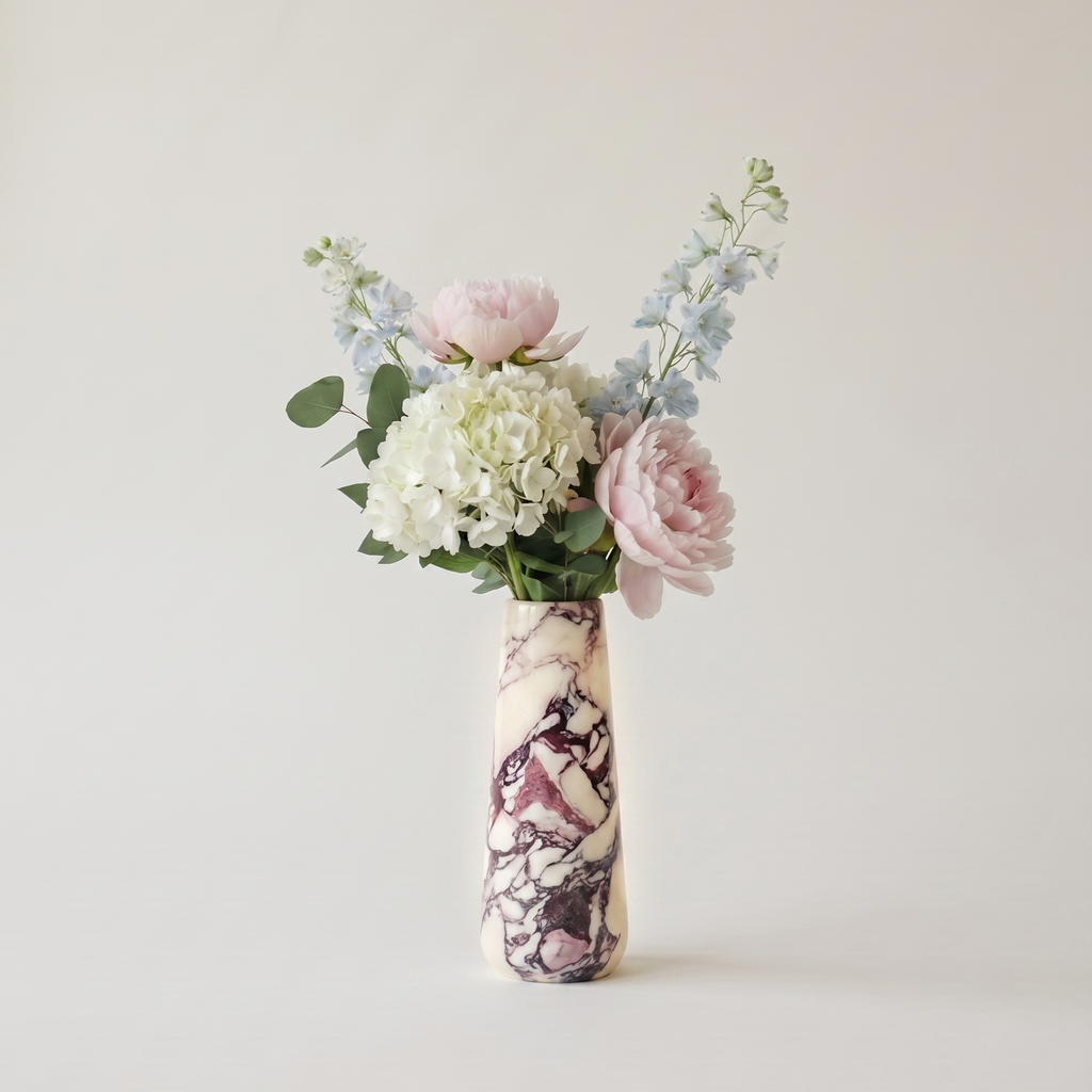 Floral arrangement in a calacatta viola marble vase on a plain background