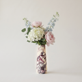 Floral arrangement in a calacatta viola marble vase on a plain background